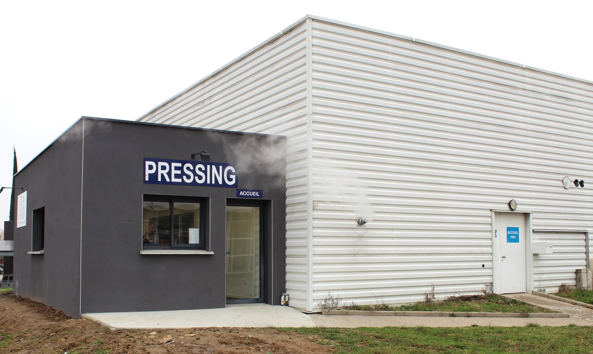 Façade du pressing AMI-DON à Loriol-sur-Drôme, avec l’entrée de l’accueil et l’accès professionnel