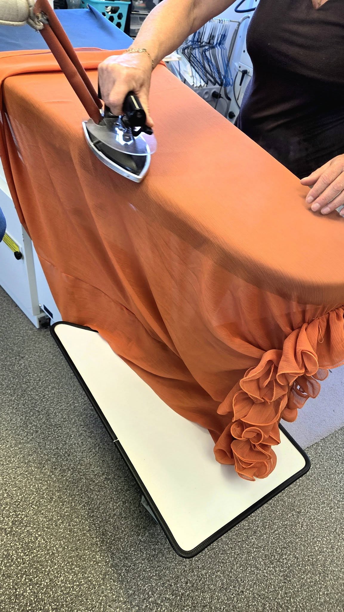 Repassage à la main d’une pièce de tissu orange dans l’atelier AMI-DON